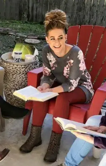Woman smiling and reading during a 12-step group session focused on addiction recovery and spirituality