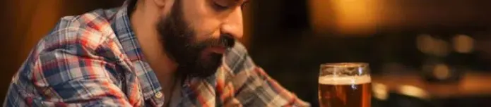 Man sitting alone with a glass of beer, reflecting the struggle of alcohol addiction.