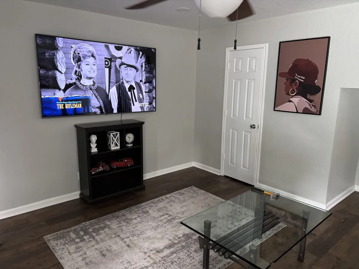 A living room in a Philadelphia sober living home, with a wall-mounted television and framed artwork