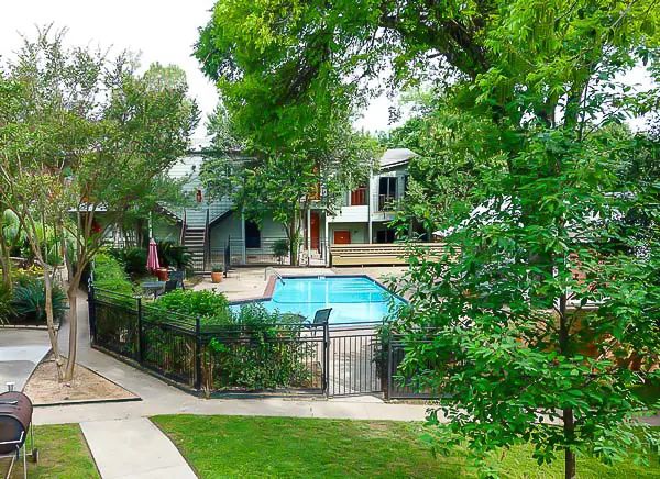 The pool and grounds of an Austin men’s sober living house, seen through the trees