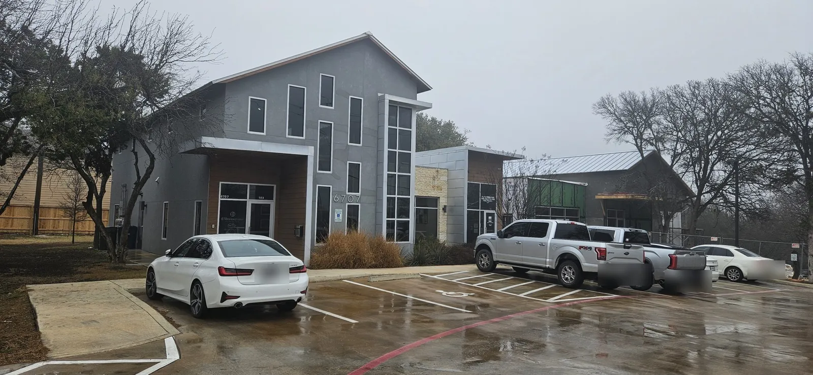 The San Antonio outpatient office: a two-story gray building with wood and glass panels beside a parking lot.